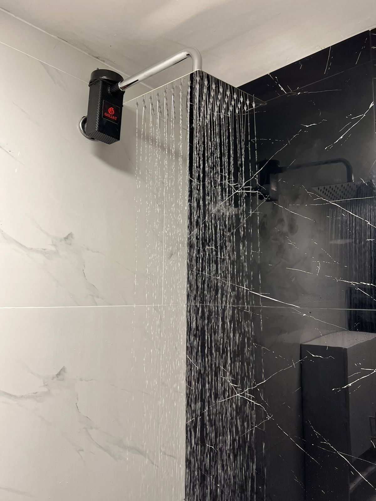 Calentador eléctrico Goliat instalado en una ducha de mármol con agua caliente